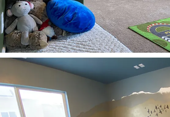 A playroom with a mountain mural, cubbies, a play kitchen and a train table